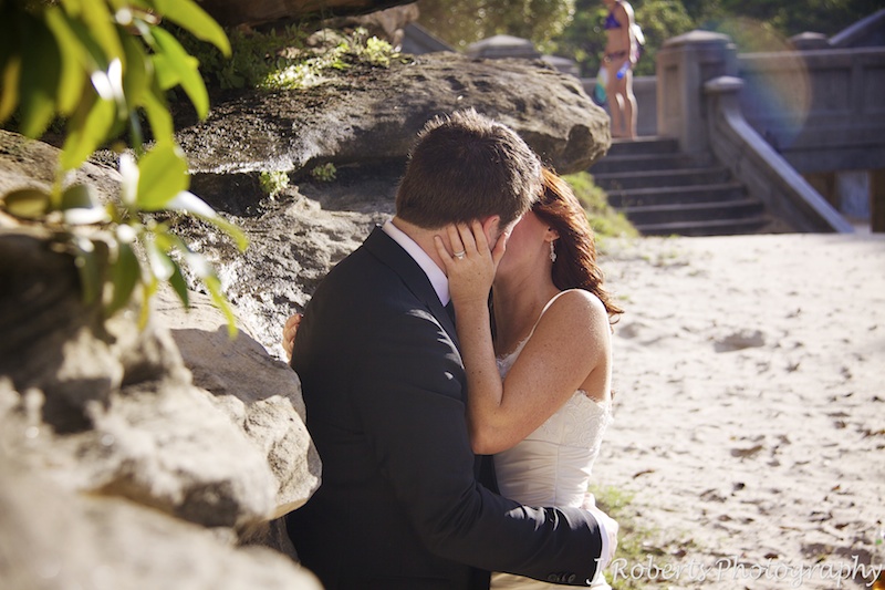 Bride and groom kissing agains rock wall - wedding photography sydney
